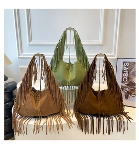 Detailed view of three bohemian suede tote bags with long fringe in earth tone colors