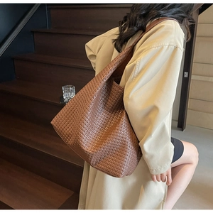 Close-up of deep brown woven leather tote bag with premium texture and shoulder strap