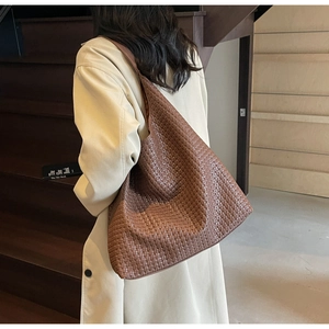 Detail of dark brown woven leather tote bag shown on model for shoulder carry style