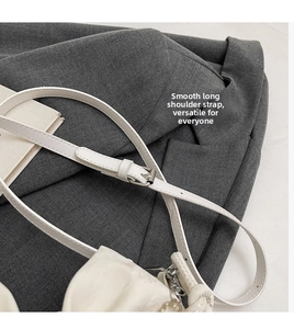 Close-up of white pleated shoulder bag with adjustable thin strap and silver metal buckle