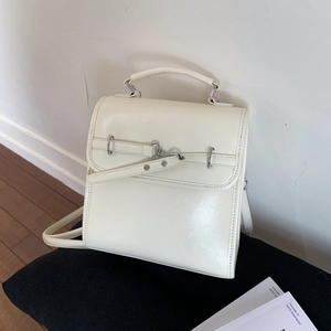 Detail of cream leather backpack with metal buckle closure and minimalist handle