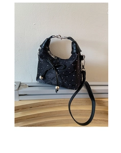 Détail du sac seau noir en tissu texturé avec strass et nœud décoratif en cuir