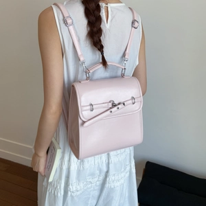 Close-up of a light pink leather backpack with flap closure and adjustable strap details