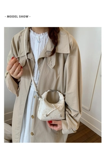 Detail of white bow handbag with metallic handle and pearlescent synthetic leather finish