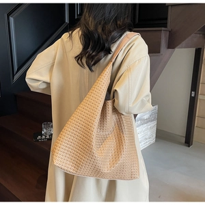 Detailed back view of a large brown woven tote bag on beige coat with city style
