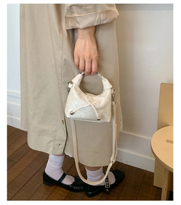 Détail du mini sac seau crème au fini brillant avec nœuds métalliques décoratifs