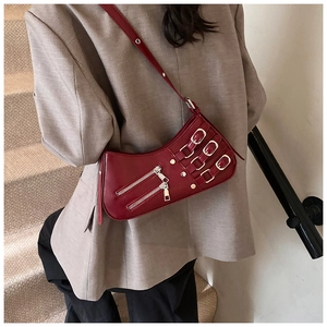 Detail shot of a dark red leather half-moon bag featuring metallic zippers and buckles
