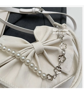 Detail of white bow handbag featuring elegant pearl and silver flower metal chains