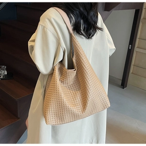 Detail of a caramel woven hobo bag showing texture and capacity on a model