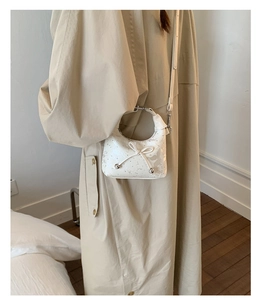 White mini bucket bag with artistic ink pattern and bow detail on trench coat model