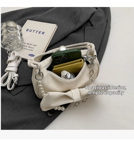 Detailed view of white bow shoulder bag interior showing storage capacity for daily essentials