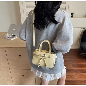 Detail of yellow bucket bag with wrinkled texture, bow decoration and leather strap