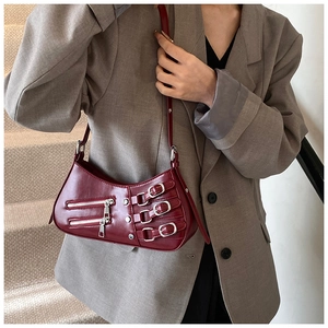 Detail of dark red punk style shoulder bag with silver zippers and metal buckles