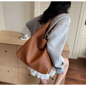 Detail of caramel brown woven leather tote bag shown on model in minimalist setting