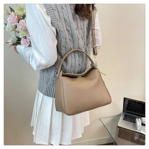 Detail of khaki pebbled leather tote bag worn as a shoulder bag in a stylish daily setting