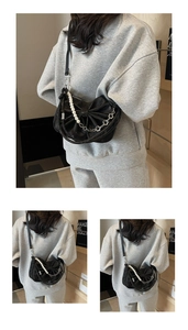 Detailed view of black bow-shaped crossbody bag with pearl chain and metal charms