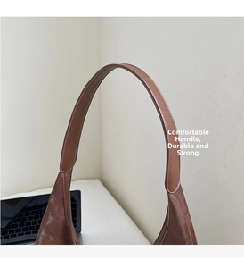 Detail showing the wide leather shoulder strap of a brown minimalist tote bag
