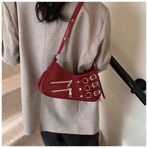 Detail view of burgundy leather crossbody bag with decorative zippers and metal buckles