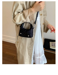 French style black bucket bag with white polka dots and a bow detail on model