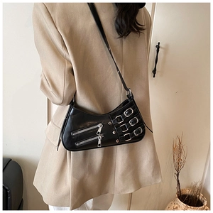 Detail of black glossy shoulder bag with silver metal buckles and punk Y2K style zippers
