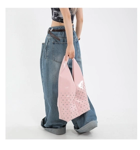 Détail du sac à bandoulière en cuir verni rose avec clous argentés et style rétro Y2K