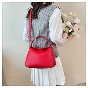 Elegant red pebbled leather tote bag carried by a model with a bouquet of flowers