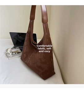 Detail of dark brown suede tote bag featuring moire texture and wide shoulder strap
