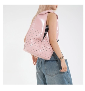 Sac à épaule Y2K en cuir verni rose avec rivets argentés porté par un mannequin