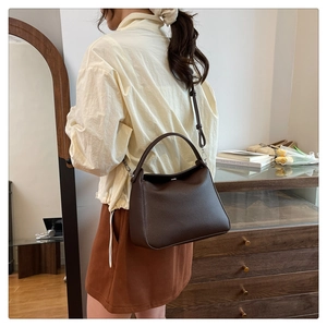 Detailed view of dark brown litchi pattern leather bag with handle and metal hardware
