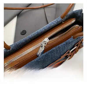 Close-up of denim handbag zipper detail with brown leather trim and silver metal hardware