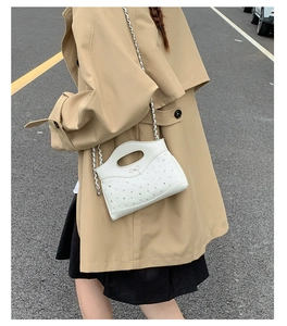 Detail of white quilted crossbody bag with sparkling rhinestones and elegant bow detail