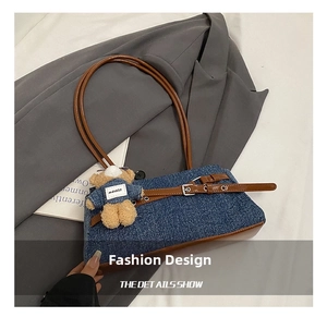 Detail of denim patchwork tote with leather belts and a cute teddy bear charm