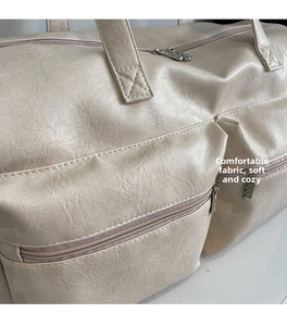 Detailed macro view of beige lychee texture leather on large capacity travel tote bag