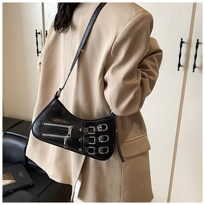 Side view of a black punk-style crescent bag with silver zippers on a beige blazer