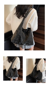 Détail du grand sac hobo noir avec texture cuir vintage porté par le modèle
