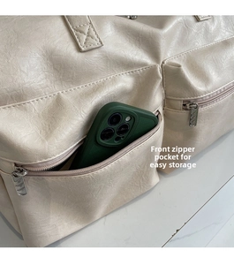 Close-up of front zipper pockets on beige tote bag showing convenient storage detail