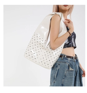 Detail of white glossy shoulder bag with silver rivet studs on high-quality leather