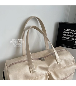 Close-up of cream PU leather duffle bag with reinforced stitching and front zip pockets