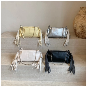 Detail of four colorful tassel chain bags displayed on a minimalist stone staircase