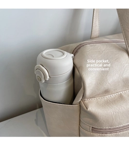 Close-up of side pocket on cream faux leather travel tote bag with a water bottle