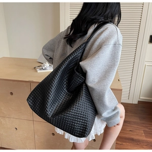 Close-up of the black woven leather texture and large capacity structure of the tote bag