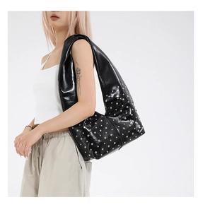Detailaufnahme einer großen schwarzen Hobo-Tasche mit Nieten aus glänzendem Leder