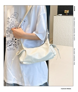 Dettaglio borsa beige in pelle lucida con coulisse laterale e trama a pieghe