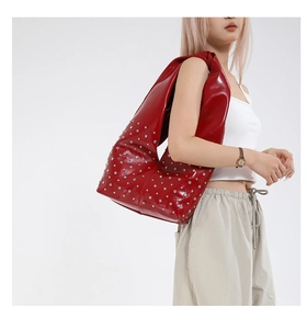 Close-up of red patent leather hobo bag featuring polished silver rivet decorations