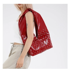 Makroaufnahme einer großen roten Lacktasche mit silbernen Nieten und Premium-Textur