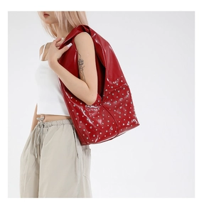 Détail d'un grand sac cabas en cuir verni rouge orné de rivets circulaires argentés