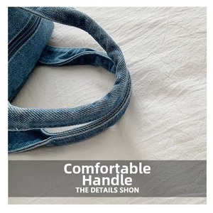 Detailed close-up of the thick cylindrical handles on a blue denim crossbody bag