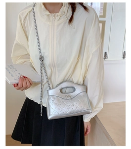Detail of silver quilted crossbody bag with rhinestone studs and metallic chain strap