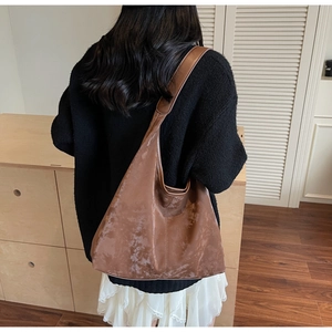 Brown large hobo shoulder bag with vintage texture shown on a model in a minimal setting