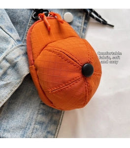 Close-up of mini orange hat-shaped bag with quilted mesh texture and a black hook